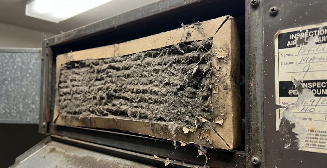 Gros plan macro d'un filtre à air CVC commercial fortement encrassé par la poussière et les débris montrant des signes évidents d'usure